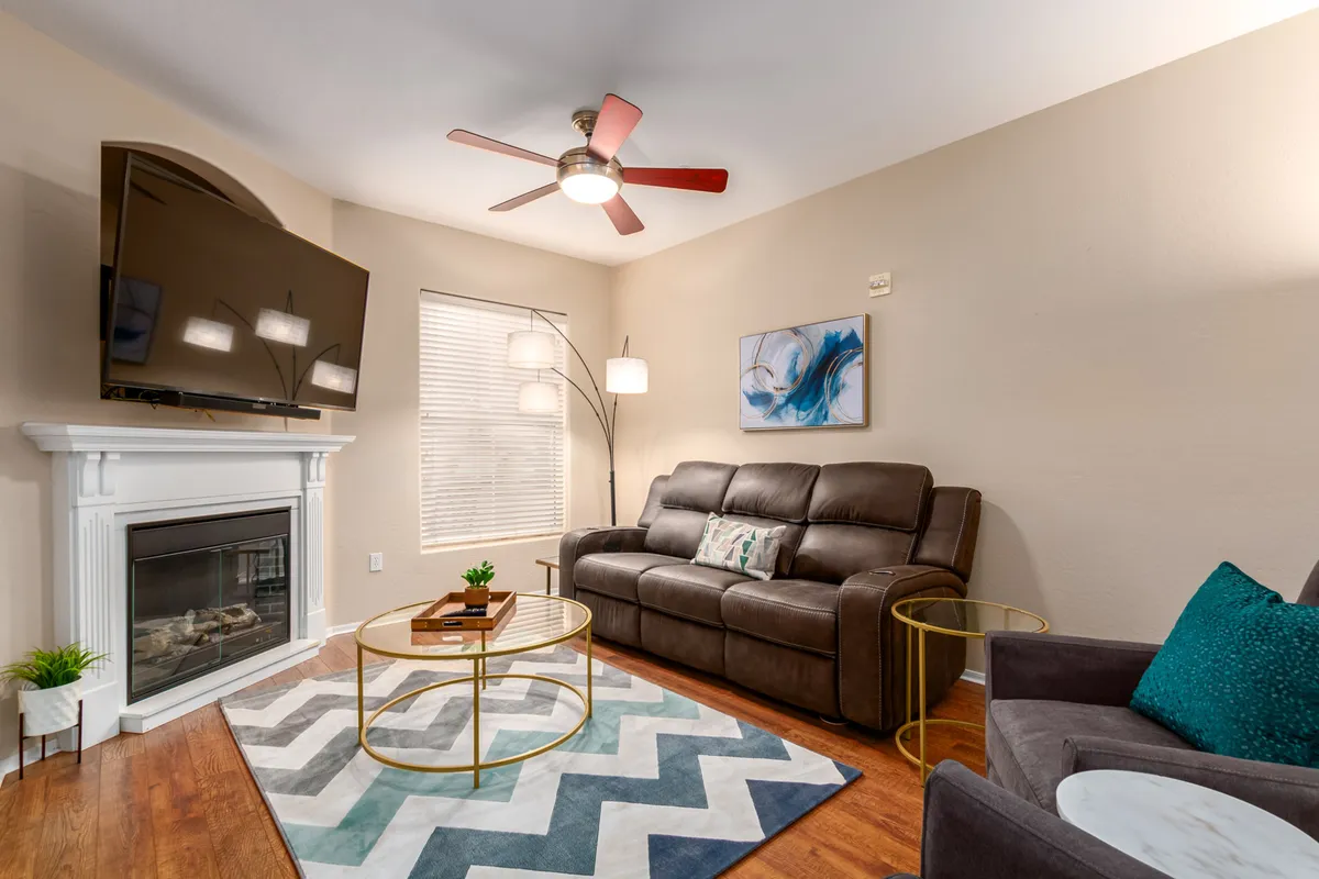 A cozy living room with a plush sofa, a coffee table, a modern television, and a warm fireplace. Art decorates the walls, and the inviting seating arrangement is ideal for relaxing evenings or socializing with friends.