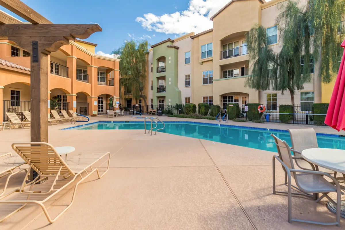 A sparkling swimming pool bordered by lounge chairs, palm trees, and colorful building facades. The area is perfect for both relaxation and socializing, inviting residents to unwind after a productive day.