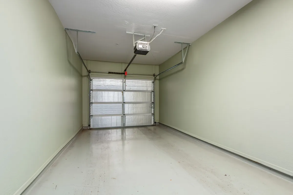 A spacious, clean interior garage with a visible garage door, smooth floors, and uncluttered walls. The space is ready for private vehicle parking or storage and evokes a sense of ease and security.