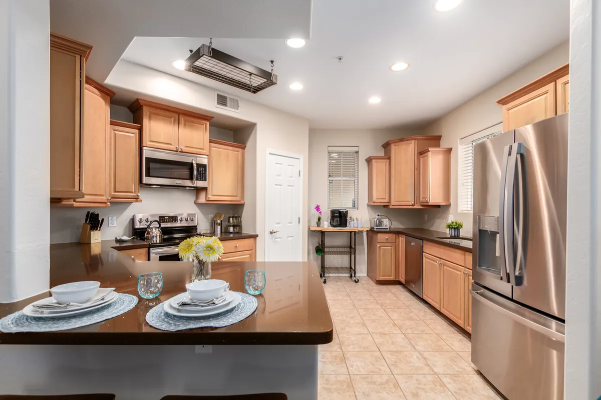 A modern kitchen with striking stainless steel appliances, elegant granite countertops, and rich wood cabinetry. The setting is staged with a dining setup, including plates and glasses, emphasizing opportunities for both cooking and entertaining. The coffee preparation area is subtly visible, tying in with the section's mention of a coffee station.